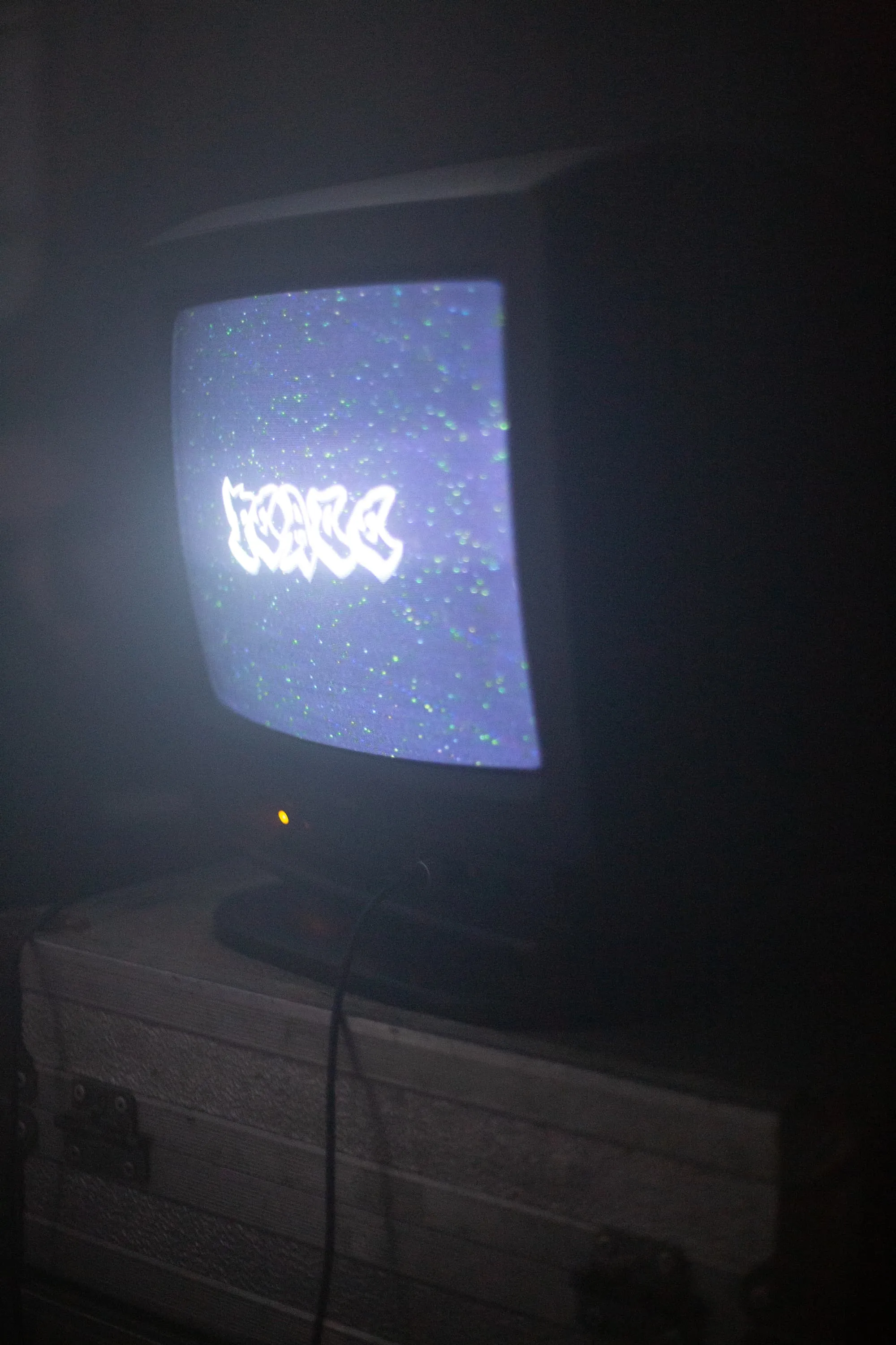 CRT TV stands on top of metal case showing the word Peace in graffiti like font with green dots surrounding it causes by interference