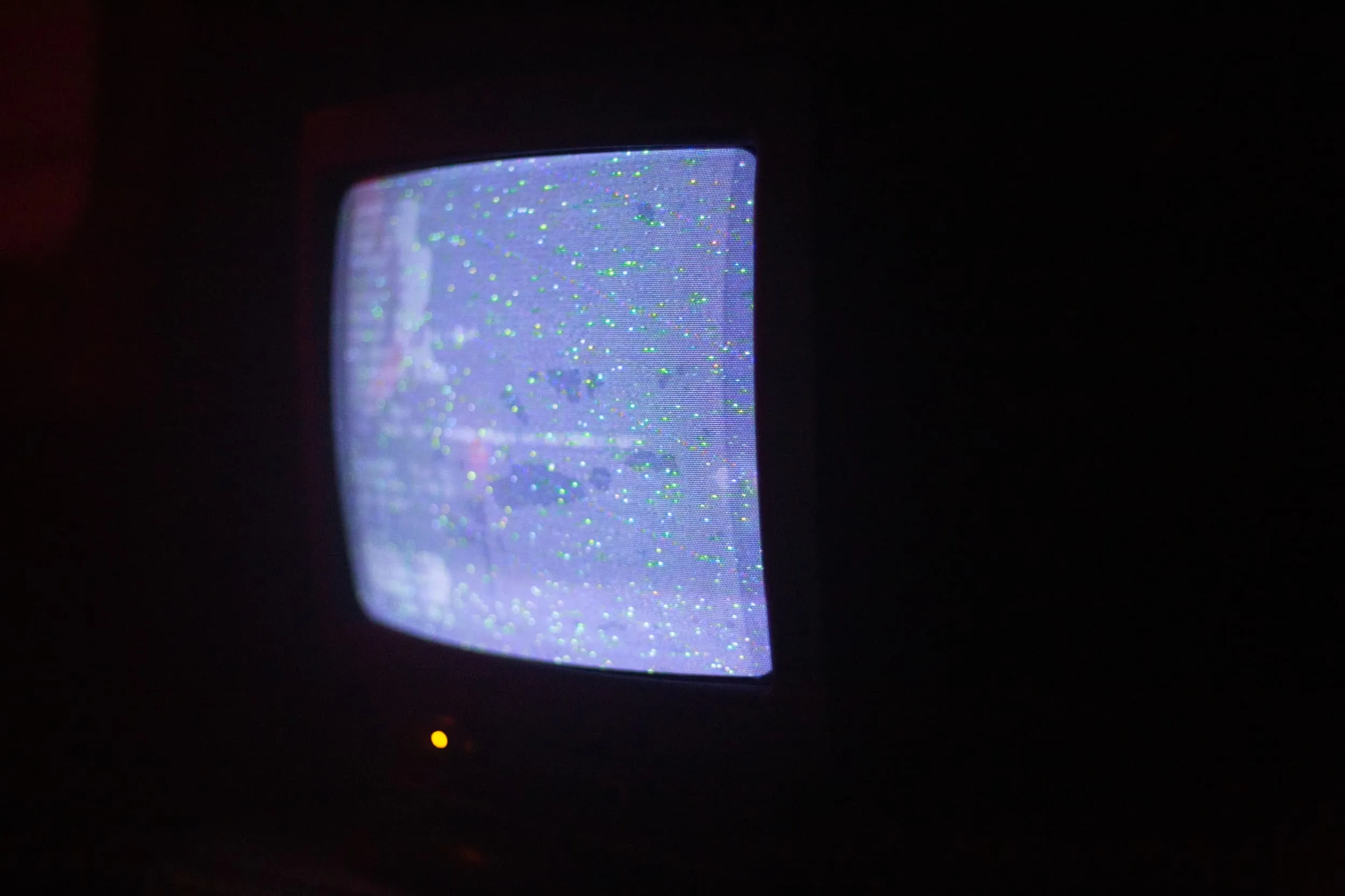A CRT TV show blurred text from computer terminal and green dots causes by interference