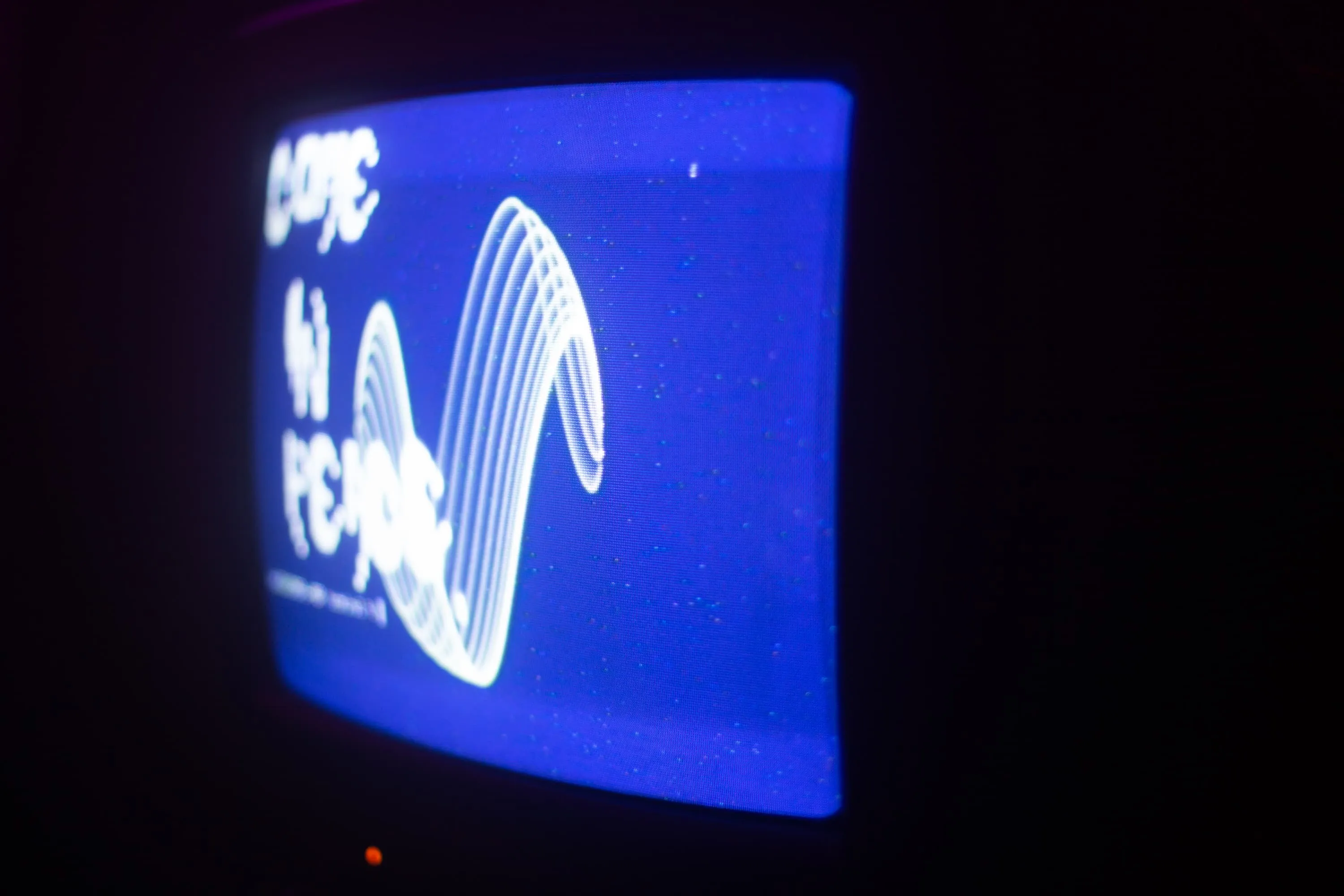CRT TV shows blue screeen with words Come In Peace on it in old computer terminal style in front of white wavy lines and green dots caused by interference