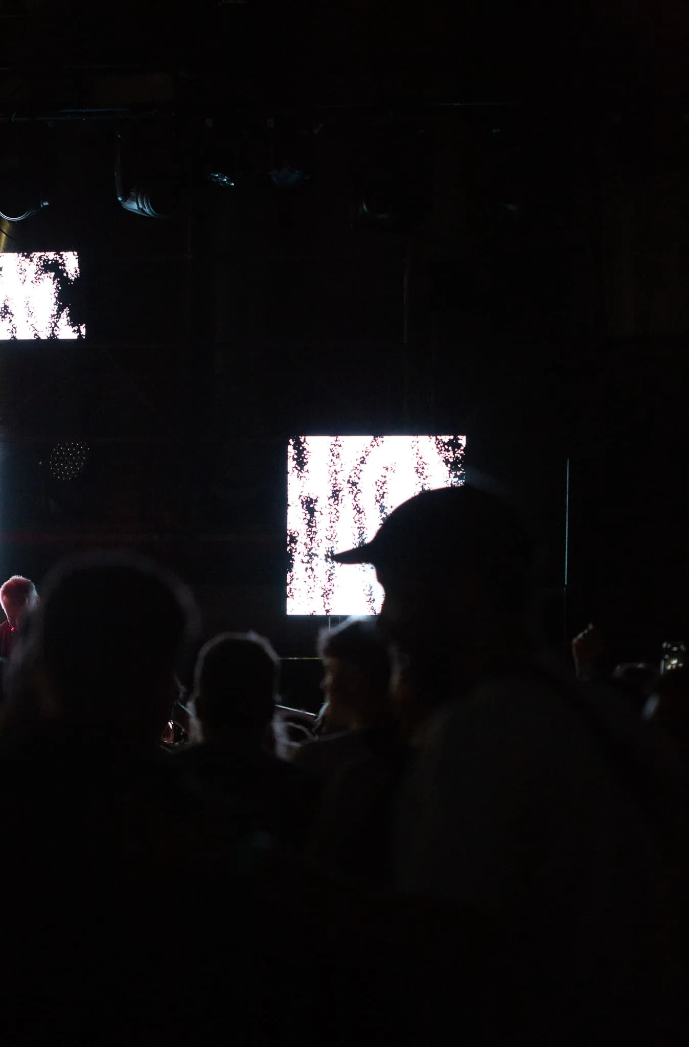 A dimly lit crowd slightly hides LED panels showing white graffiti visuals.