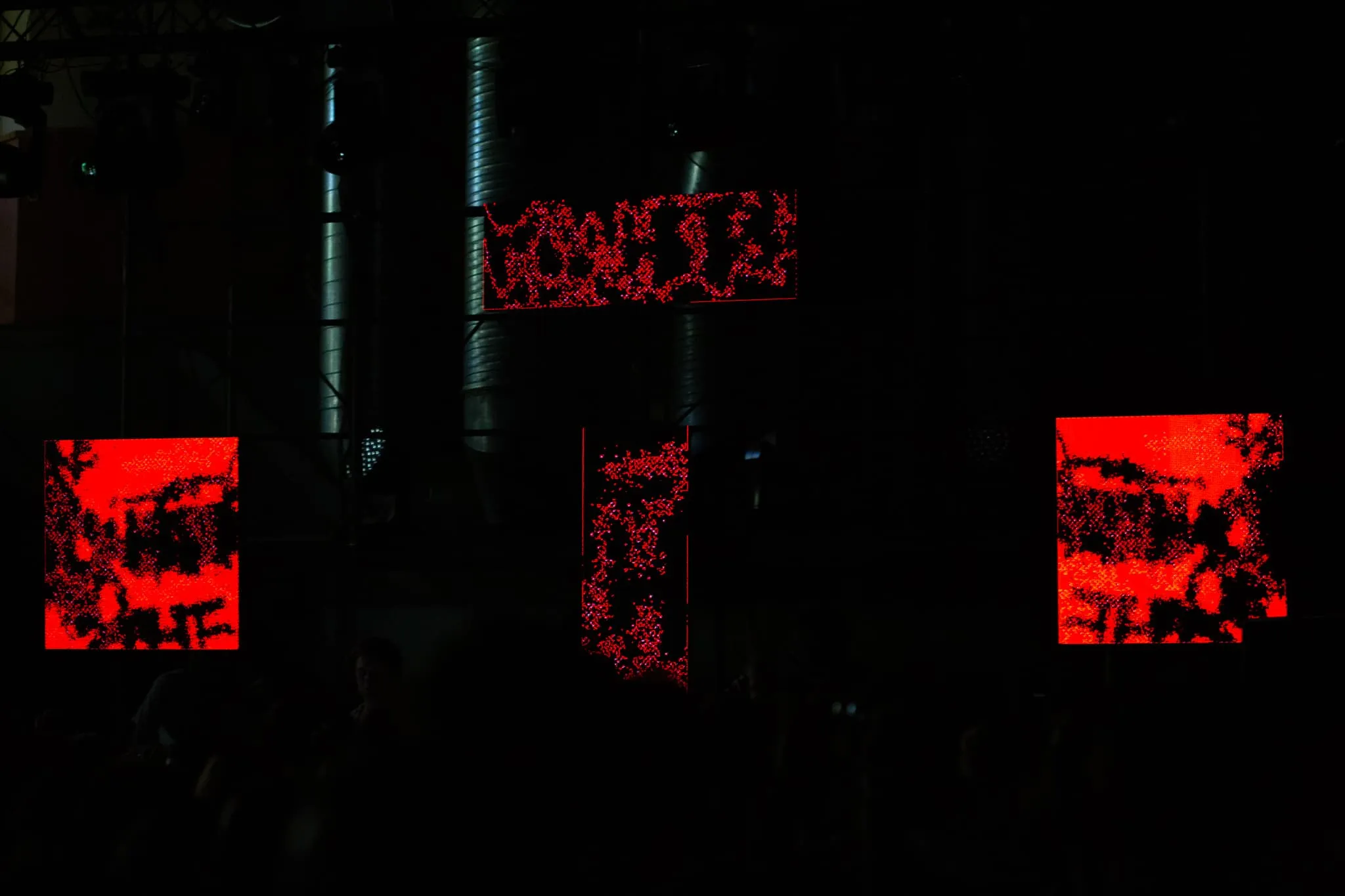 4 LED panels attatched to scaffolding in dark environment showing red distrorted graffiti