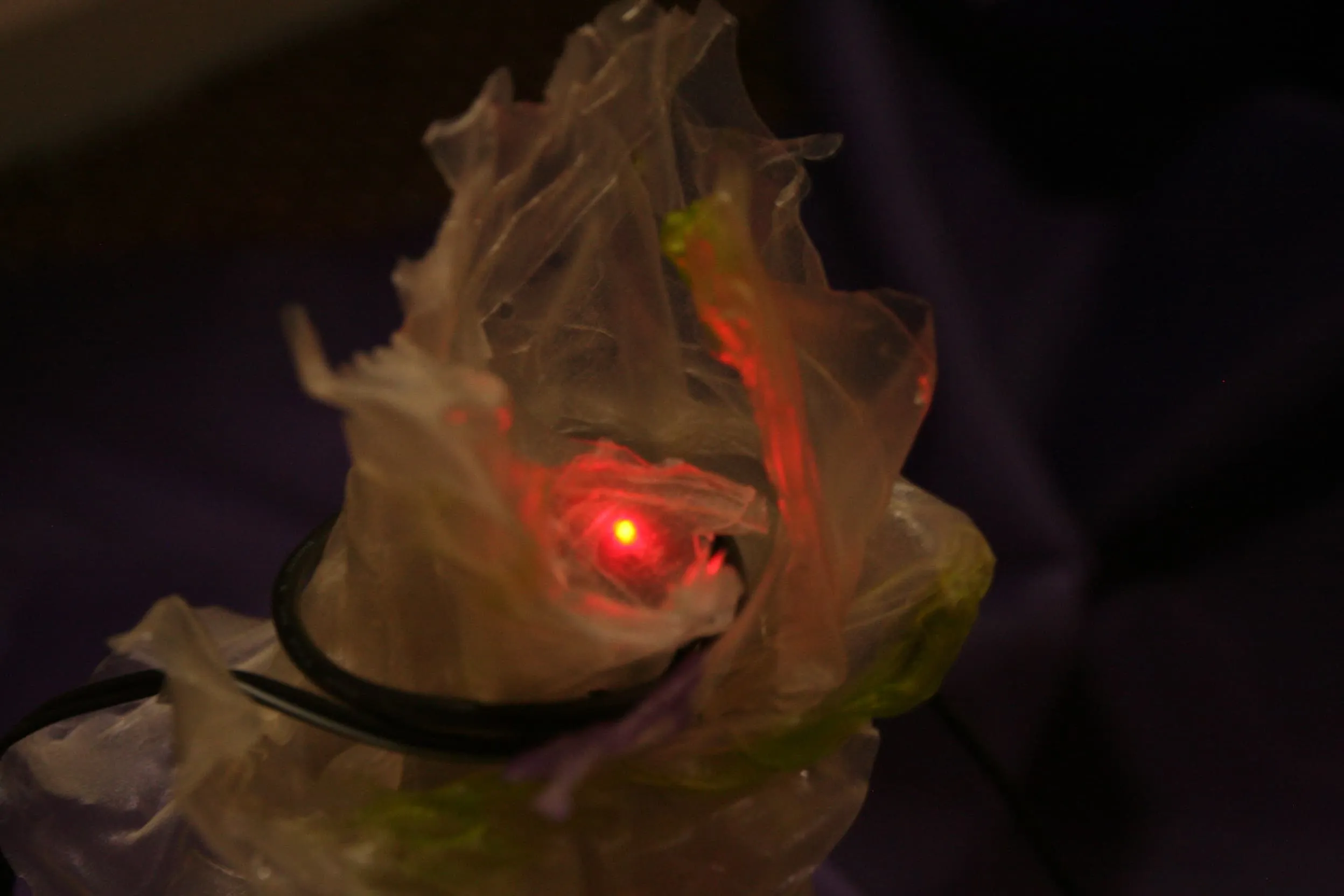 Closeup image of transparent rice paper wrapped around a arduino with a small red light eminating from it.