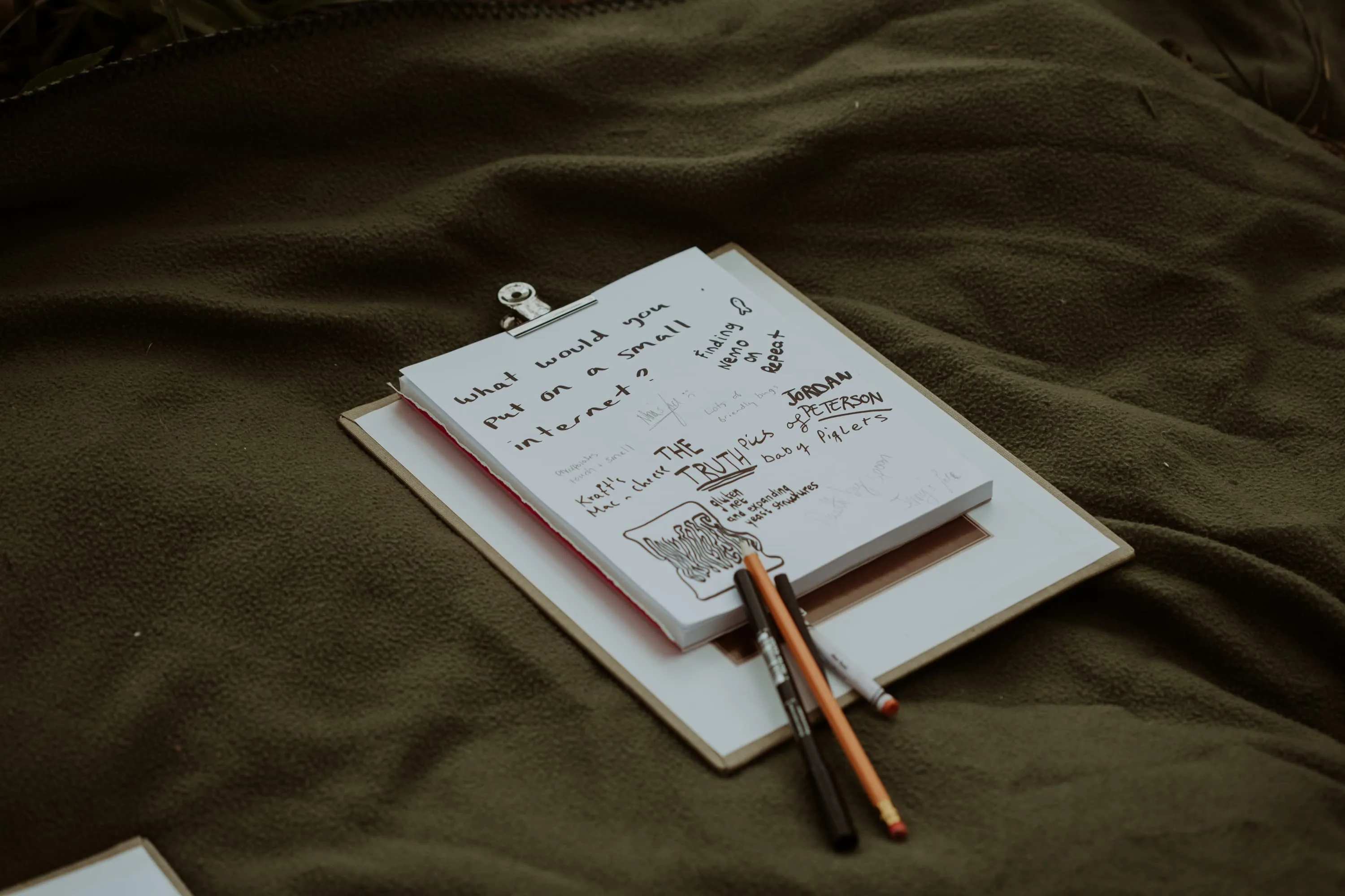 Clickboard sitting on a green blanket has hand written responses including finding nemo to the question, what would you put on a small internet?