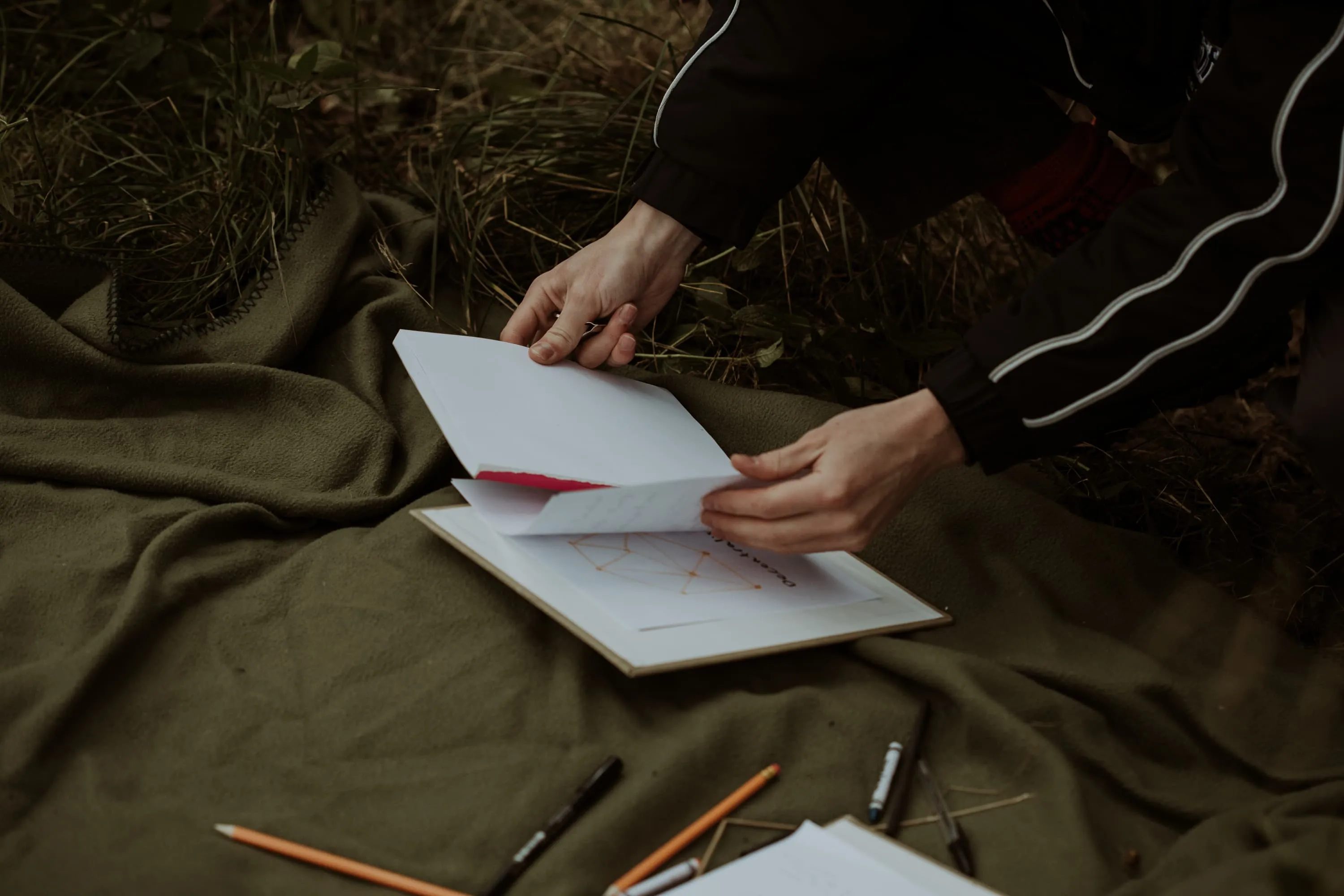 White man holds a notepad above a clipboard that is sitting on a green blanket, slightly covered is a diagram of a decentralised network