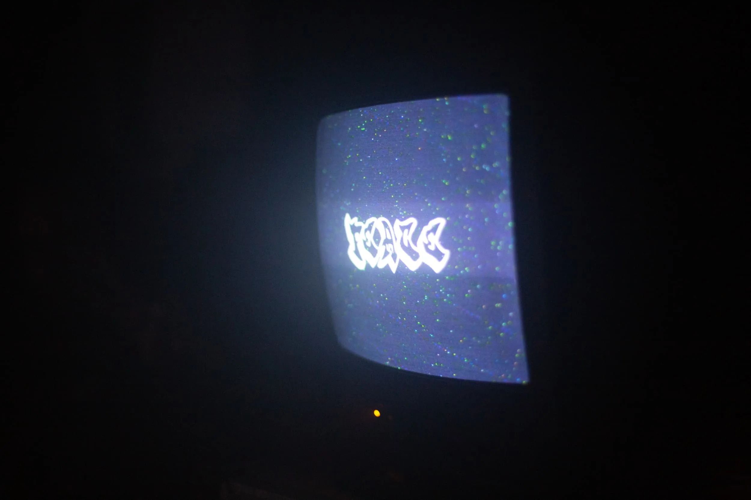 CRT TV shows text Peace in a graffiti font in the dark