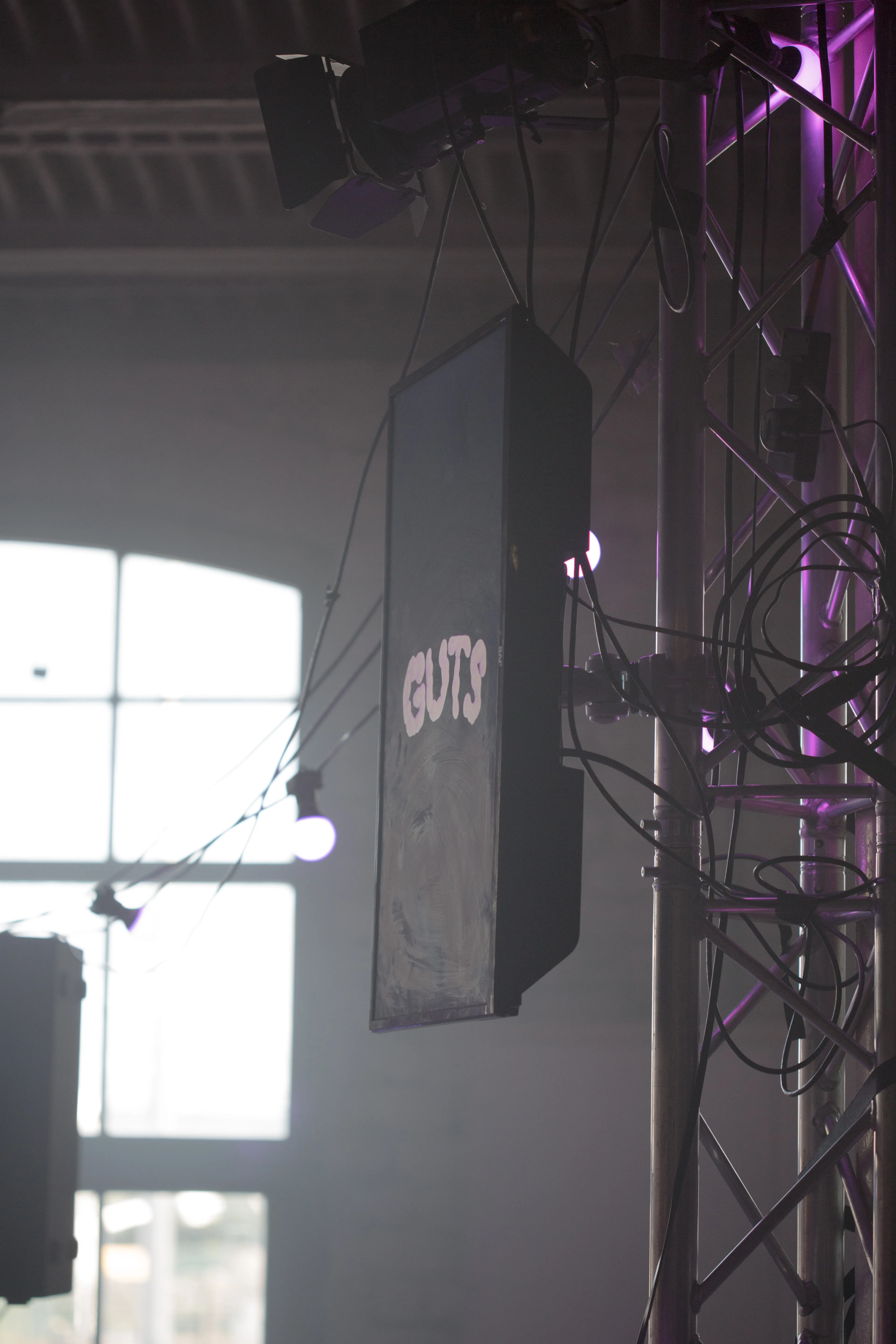 TV with 3D wobbly text reading GUTS is attached to a steel truss