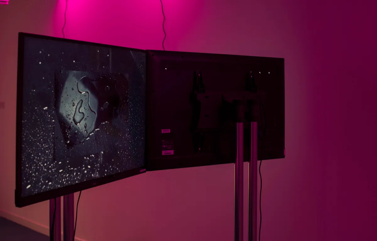 Pink hue fills the space with two TVs facing opposite direction show Lavendar Heated to 60c film.