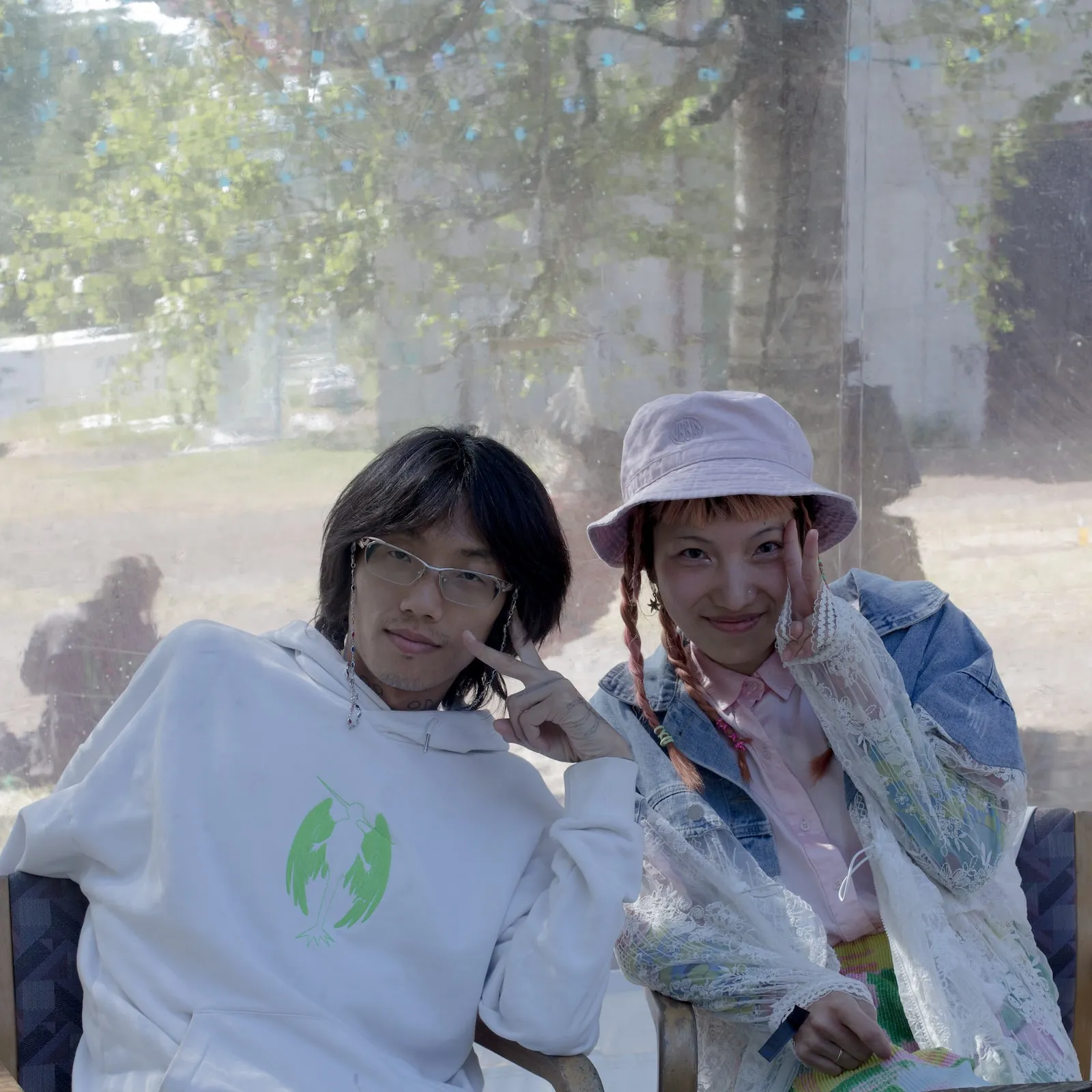 Two people smile and make the peace symbol sitting